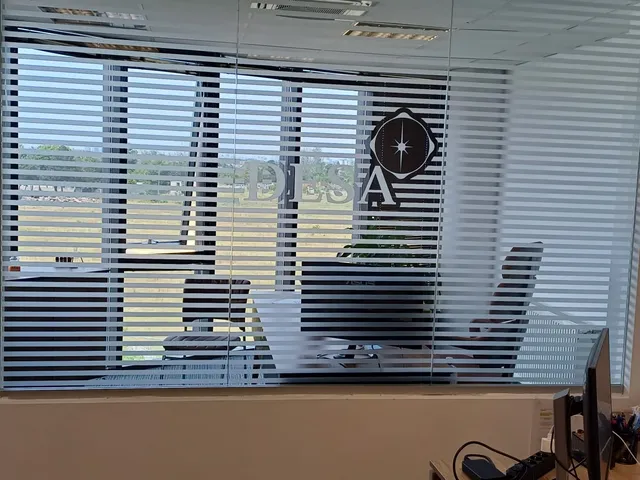 Folie sablată cu benzi orizontale și logo decupat pe perete de sticlă, birou
